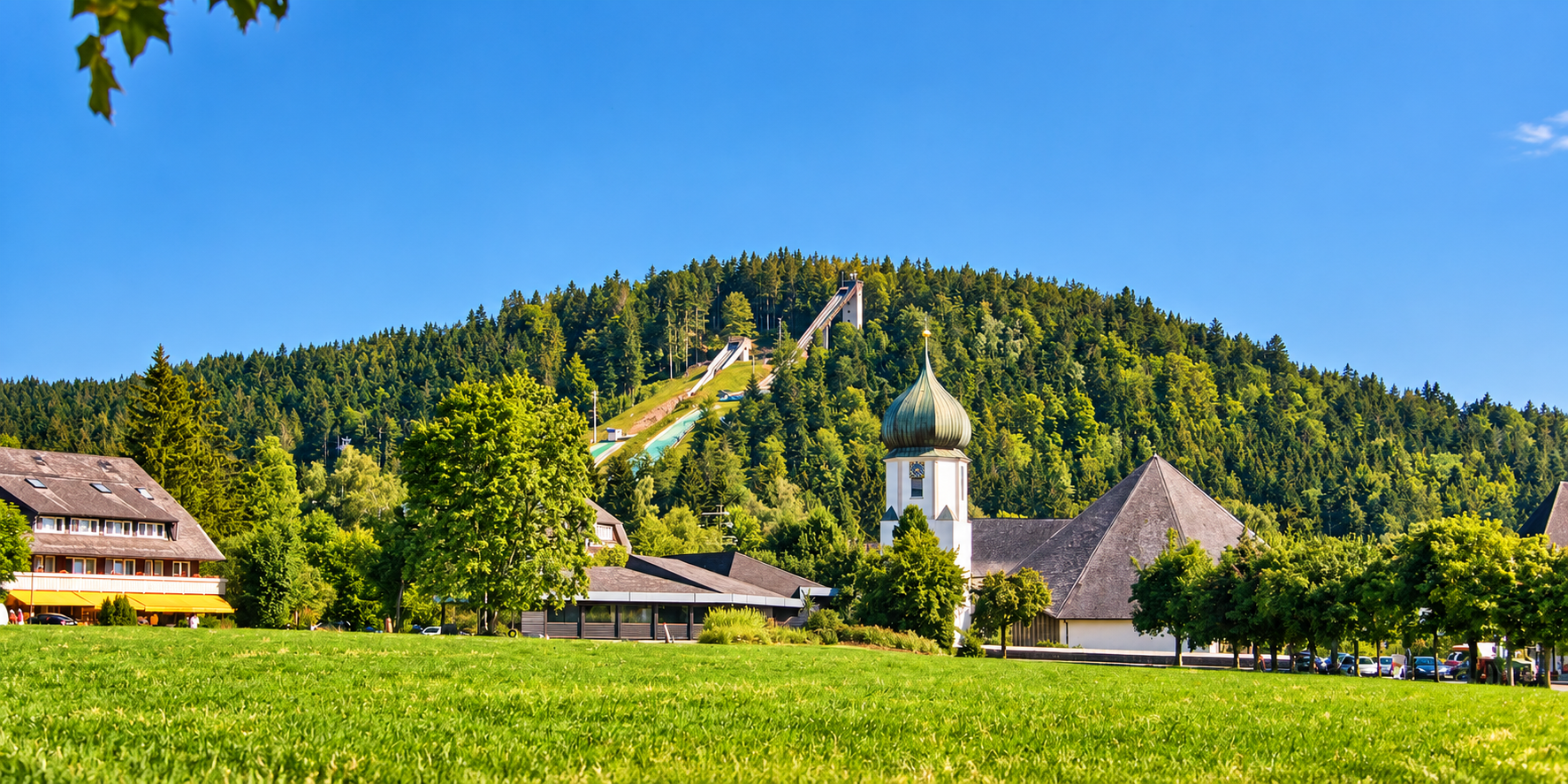 Blick auf Hinterzarten mit Kirche und Adlerschanze, links das Gebäude von Juwelier Wagner Reinhardt